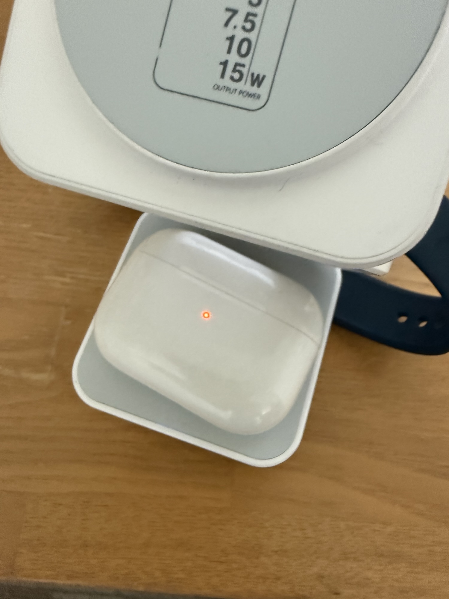 3-in-1ワイヤレス充電器のベース部分でAirPodsを充電中。本体に5/7.5/10/15Wの出力表記が見える